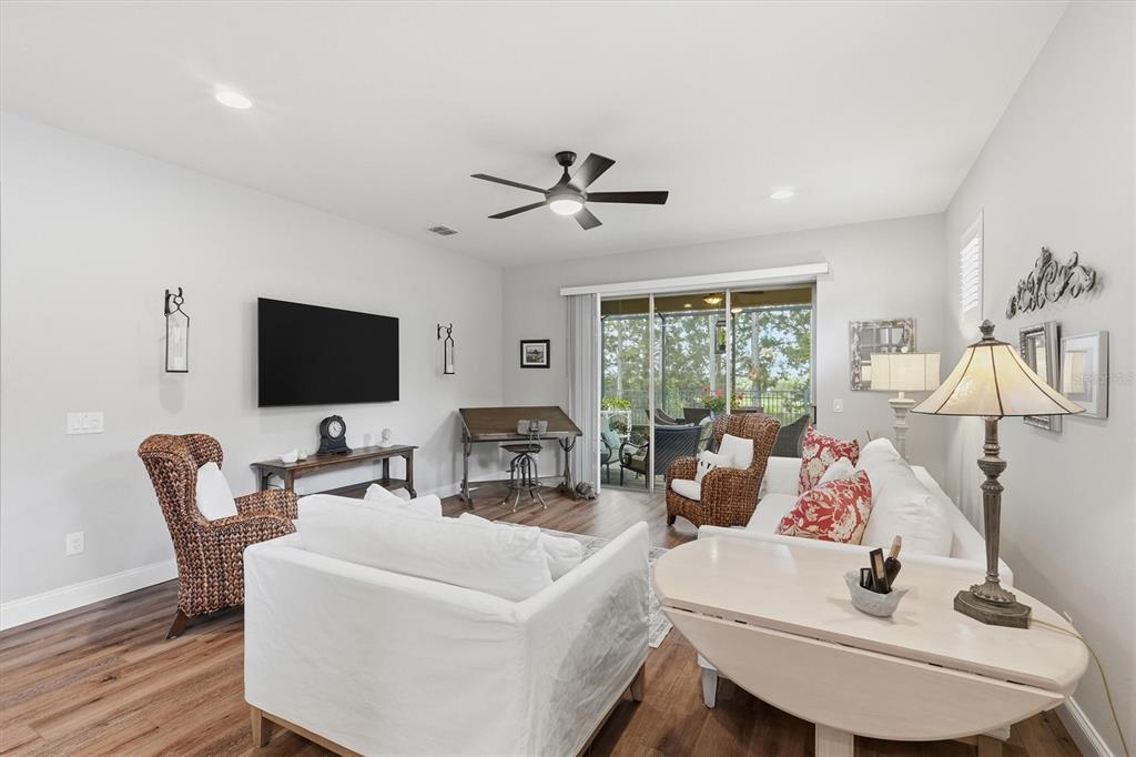 A living room features white furniture, wicker armchairs, a television, and a sliding glass door — 10049 SW 77TH LOOP, OCALA, FL