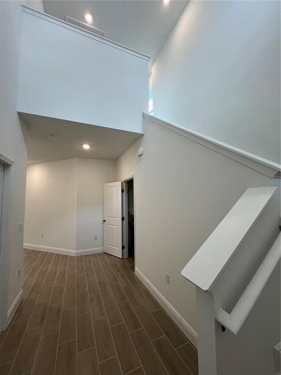 A bright entryway features wood-look tile flooring, white walls, and a staircase with a railing — 2213 JUNIPER BERRY AVENUE, MINNEOLA, FL