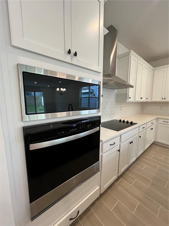 A modern kitchen features white cabinetry, stainless steel appliances, and light-colored tile flooring — 2213 JUNIPER BERRY AVENUE, MINNEOLA, FL
