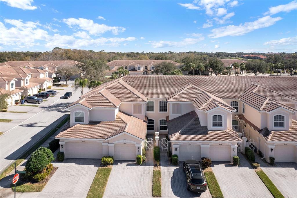 An aerial view shows a row of beige townhouses with tiled roofs and paved driveways — 4533 CINNAMON DRIVE UNIT 2707, SARASOTA, FL