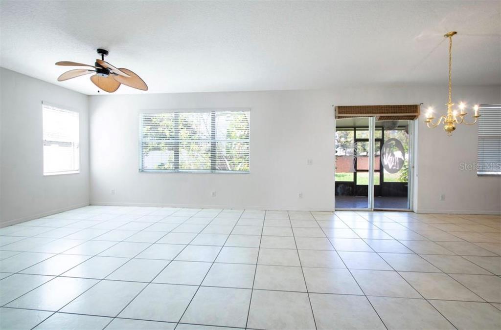 A bright, tiled living area features a ceiling fan, large windows, and a sliding glass door — 1412 BLACKWATER POND DRIVE, ORLANDO, FL