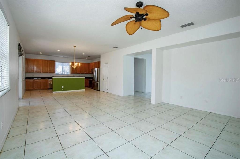 An open-concept living area features light tile flooring, a ceiling fan, and a kitchen — 1412 BLACKWATER POND DRIVE, ORLANDO, FL