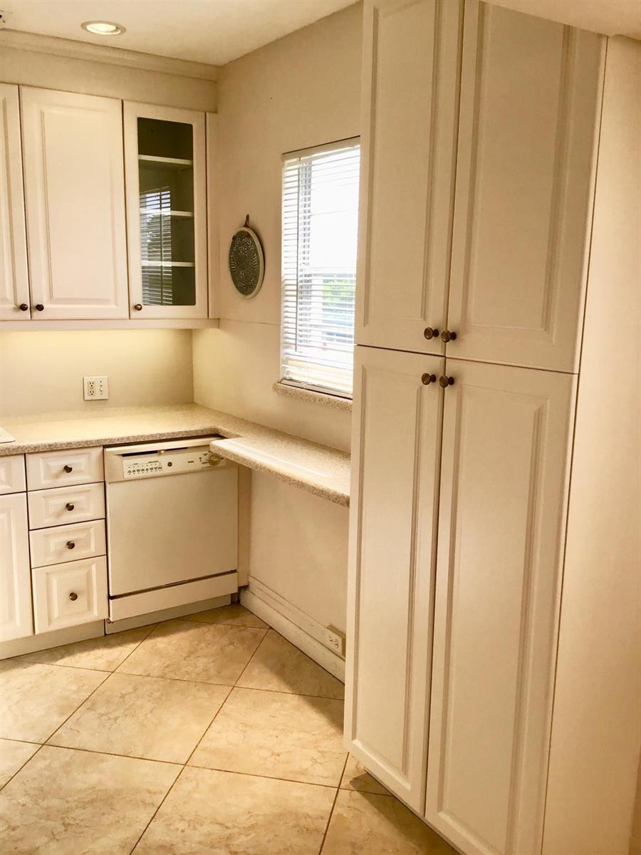 A kitchen features white cabinets, a dishwasher, a tall pantry, and light-colored tile flooring — 336 Brighton H # 336, Boca Raton FL 33434, BOCA RATON, FL