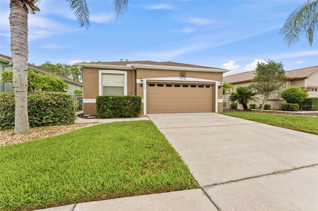 A single-story house with a tan stucco exterior, a two-car garage, and a concrete driveway — 7606 BERNA LANE, LAND O LAKES, FL