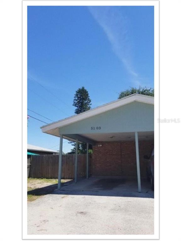 A covered carport with a brick wall and a concrete driveway under a blue sky — 5103 34TH STREET W, BRADENTON, FL