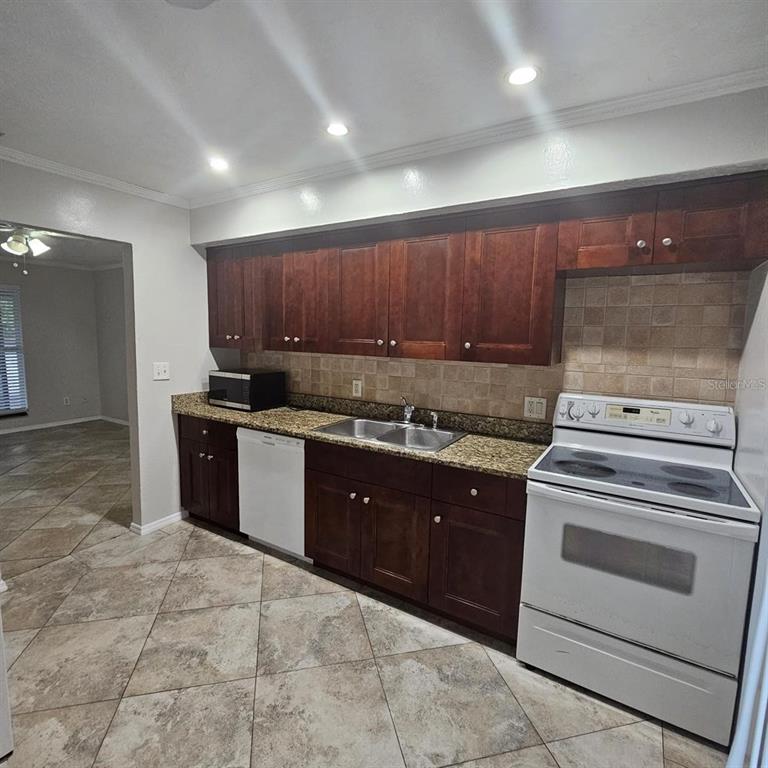 A kitchen with dark wood cabinets, granite countertops, tile flooring, and white appliances — 5103 34TH STREET W, BRADENTON, FL