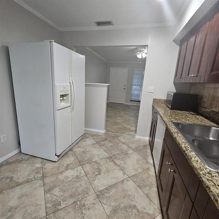 A kitchen with dark wood cabinets, granite countertops, and a white refrigerator — 5103 34TH STREET W, BRADENTON, FL