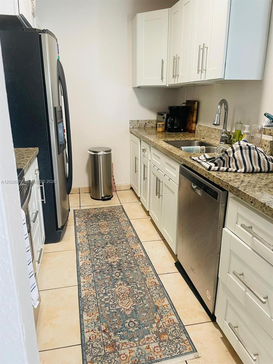 A galley kitchen features white cabinets, granite countertops, stainless steel appliances, and a patterned runner — 10393 N Kendall Dr # U6, Miami FL 33176, MIAMI, FL