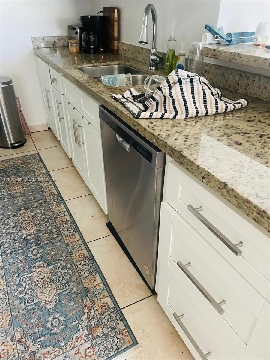A kitchen features white cabinets, granite countertops, a stainless steel dishwasher, and a patterned rug — 10393 N Kendall Dr # U6, Miami FL 33176, MIAMI, FL