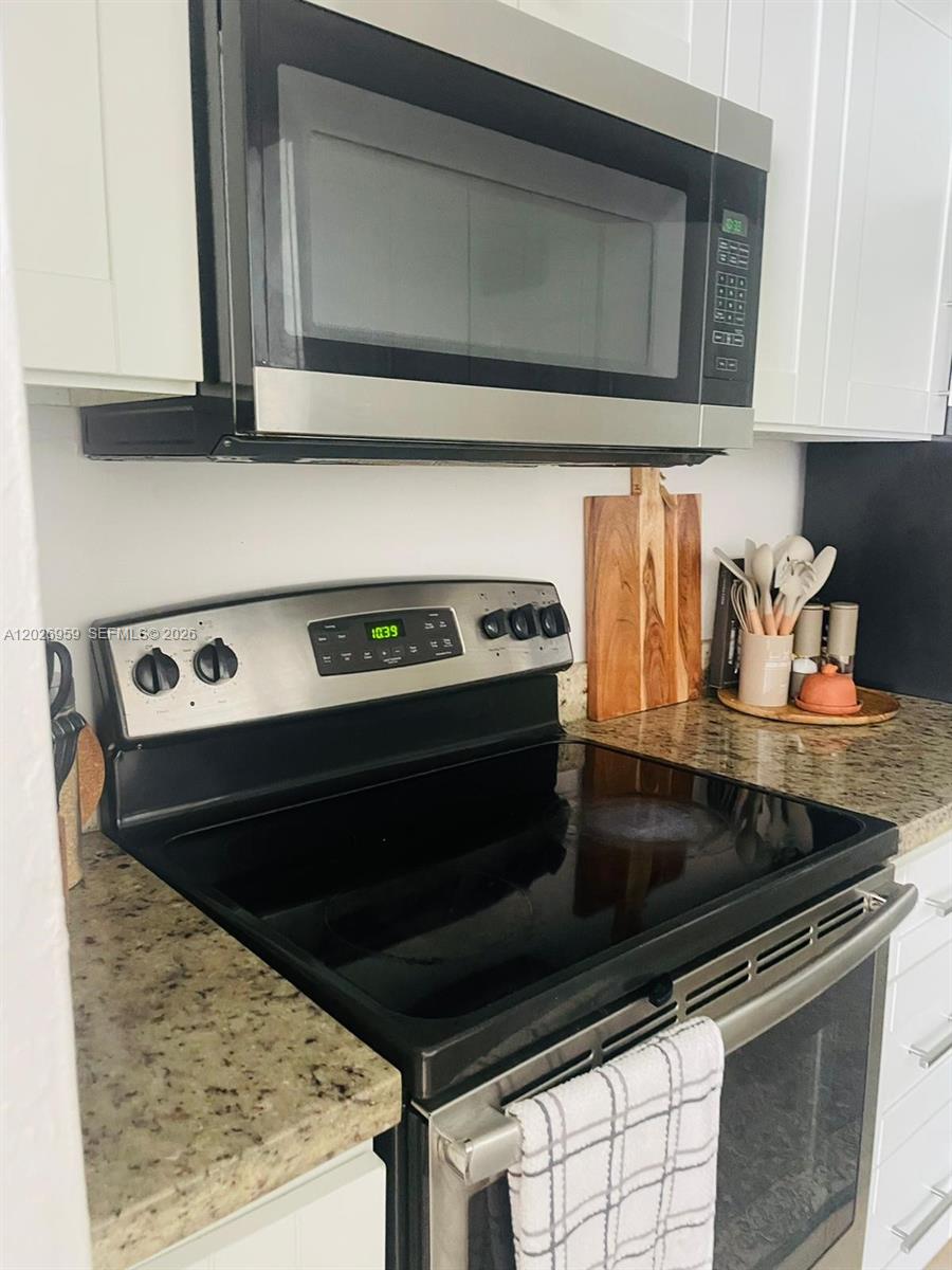 A kitchen features a stainless steel microwave, a black electric range, and granite countertops — 10393 N Kendall Dr # U6, Miami FL 33176, MIAMI, FL
