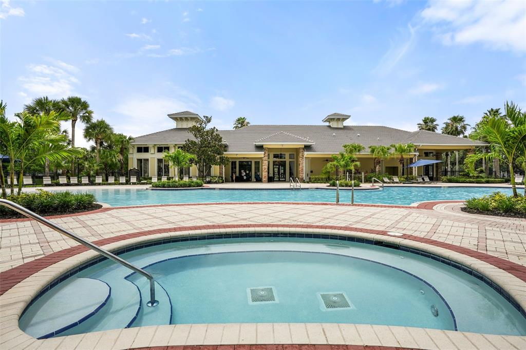 A circular hot tub sits in the foreground before a large swimming pool and clubhouse — 14432 CLARKSON DRIVE, ORLANDO, FL