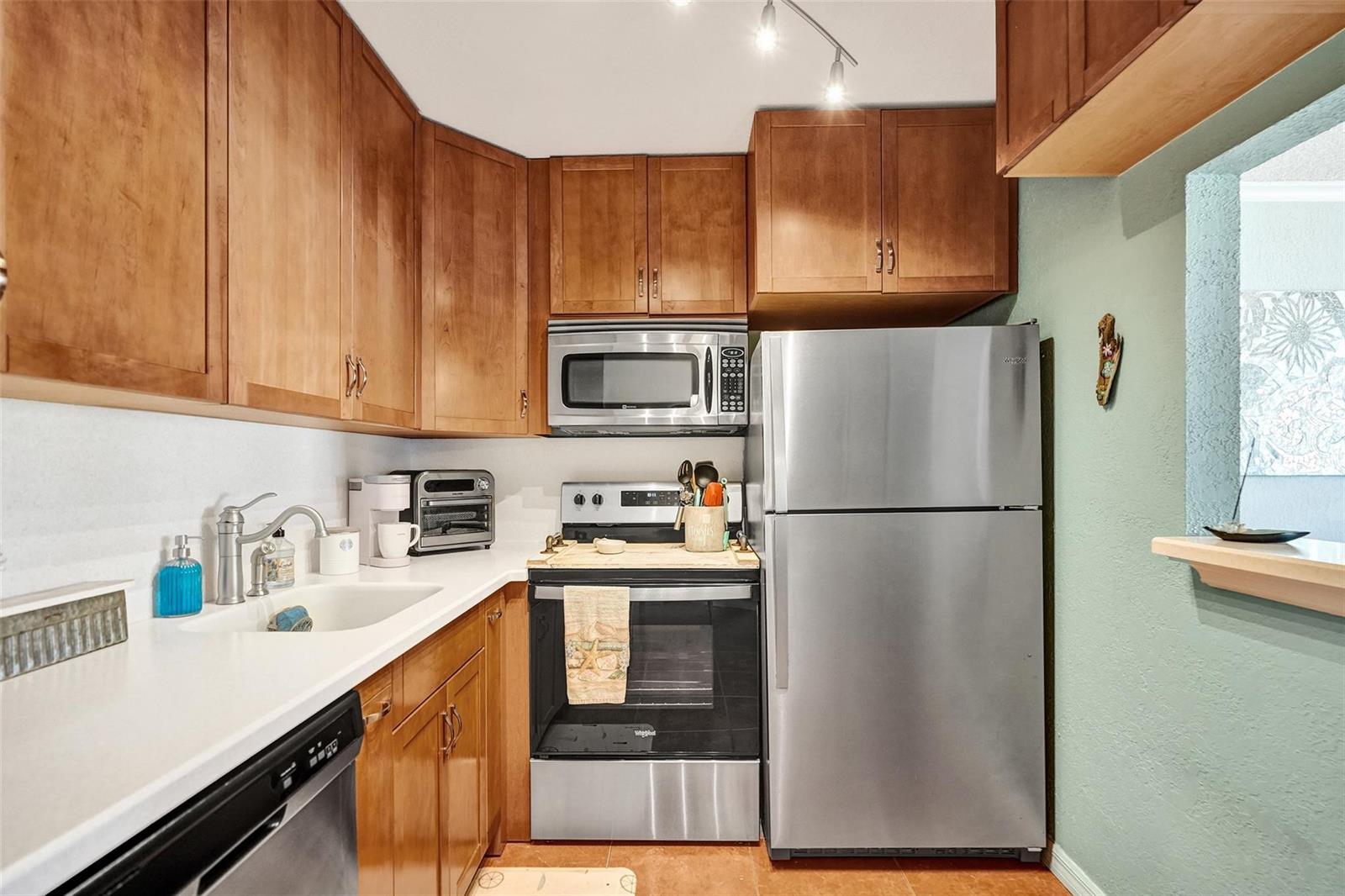 A kitchen features wood cabinets, stainless steel appliances, white countertops, and a light green wall — 227 Tilford K # 227, Deerfield Beach FL 33442, DEERFIELD BEACH, FL
