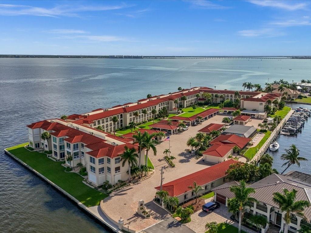 An aerial view of a waterfront apartment complex with red tile roofs and boat docks — 1 COLONY POINT DRIVE UNIT 1C, PUNTA GORDA, FL