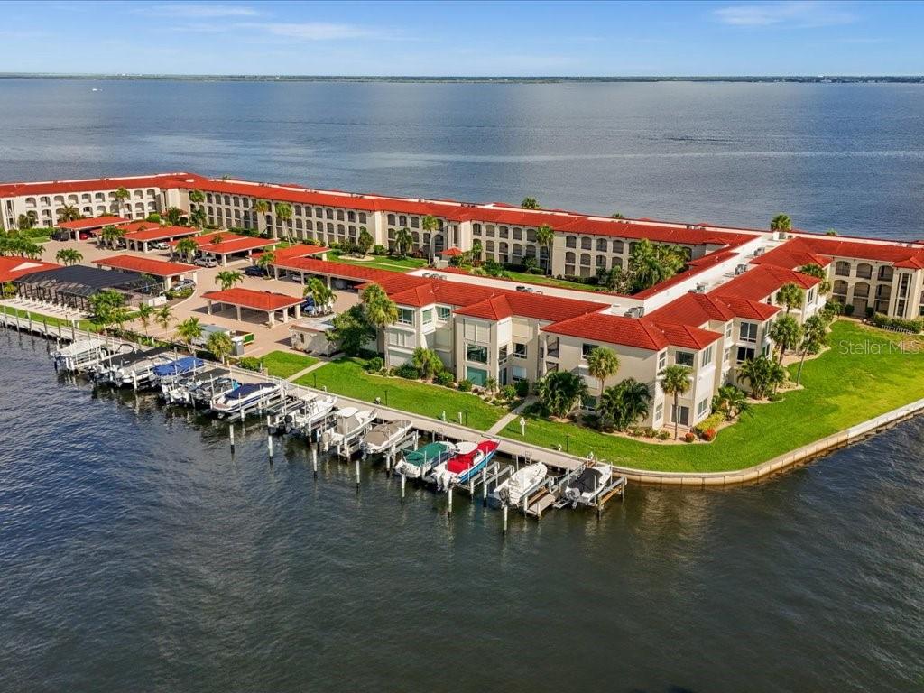 An aerial view of a waterfront condominium complex with a red tile roof and boat slips — 1 COLONY POINT DRIVE UNIT 1C, PUNTA GORDA, FL