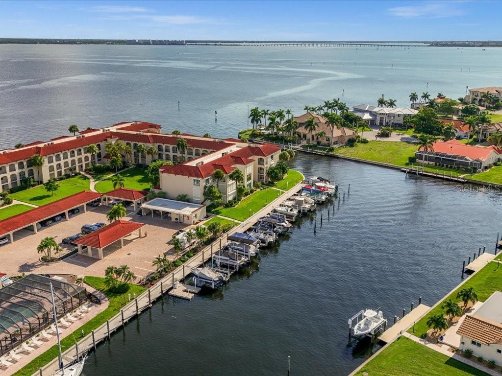 An aerial view of a waterfront apartment complex with a boat dock and canal — 1 COLONY POINT DRIVE UNIT 1C, PUNTA GORDA, FL