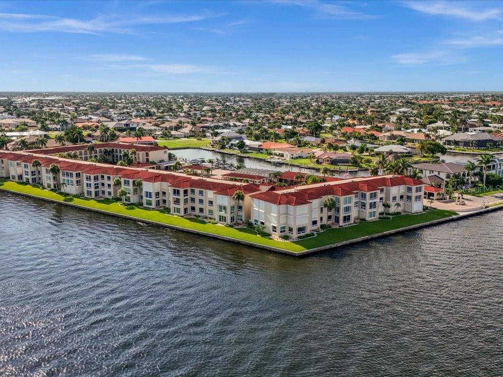 An aerial view of a multi-story waterfront apartment complex with red tile roofs — 1 COLONY POINT DRIVE UNIT 1C, PUNTA GORDA, FL