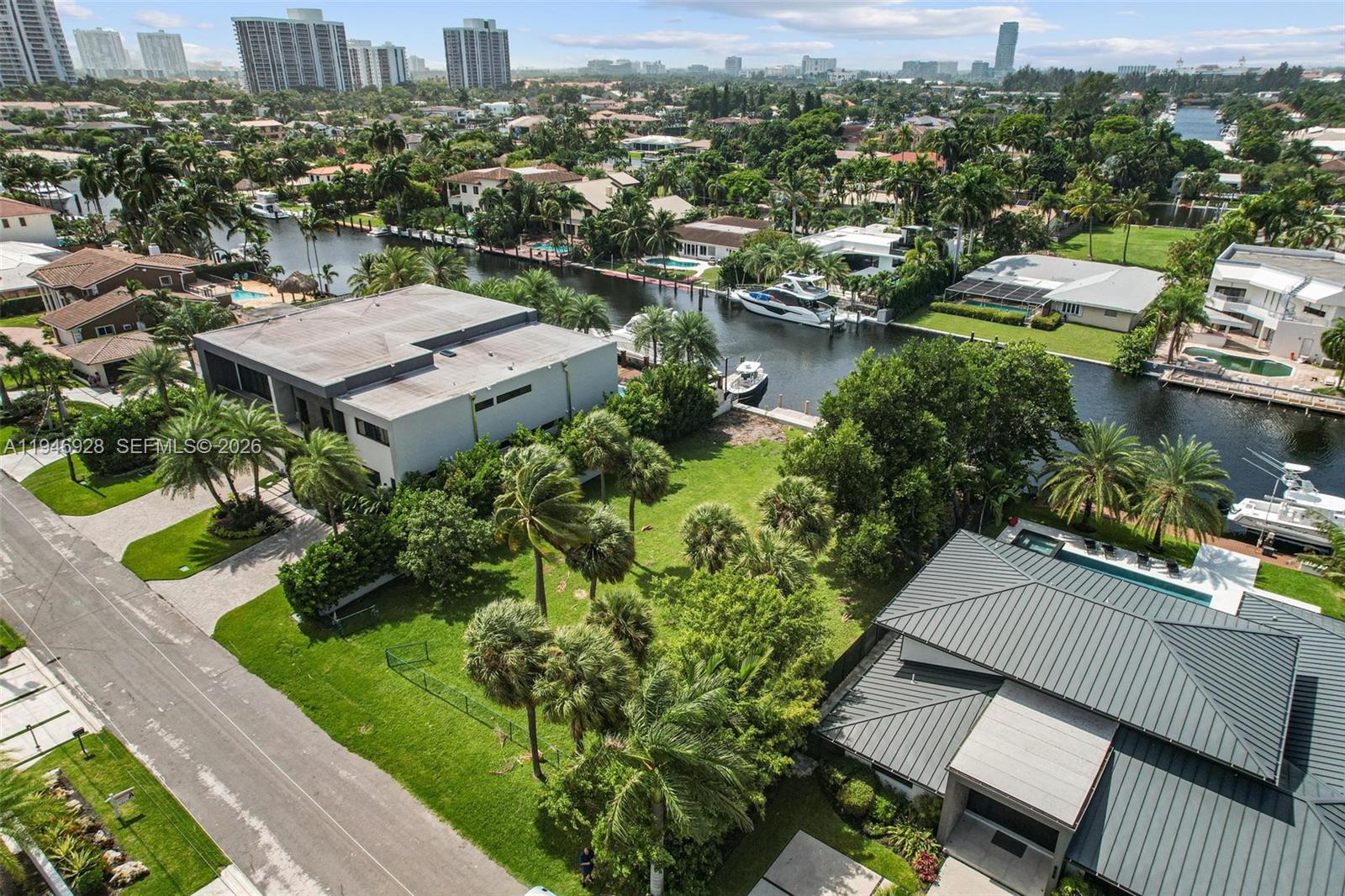 An aerial view shows a residential neighborhood with waterfront homes, private docks, and lush landscaping — 606 Palm Dr, Hallandale Beach FL 33009, HALLANDALE BEACH, FL