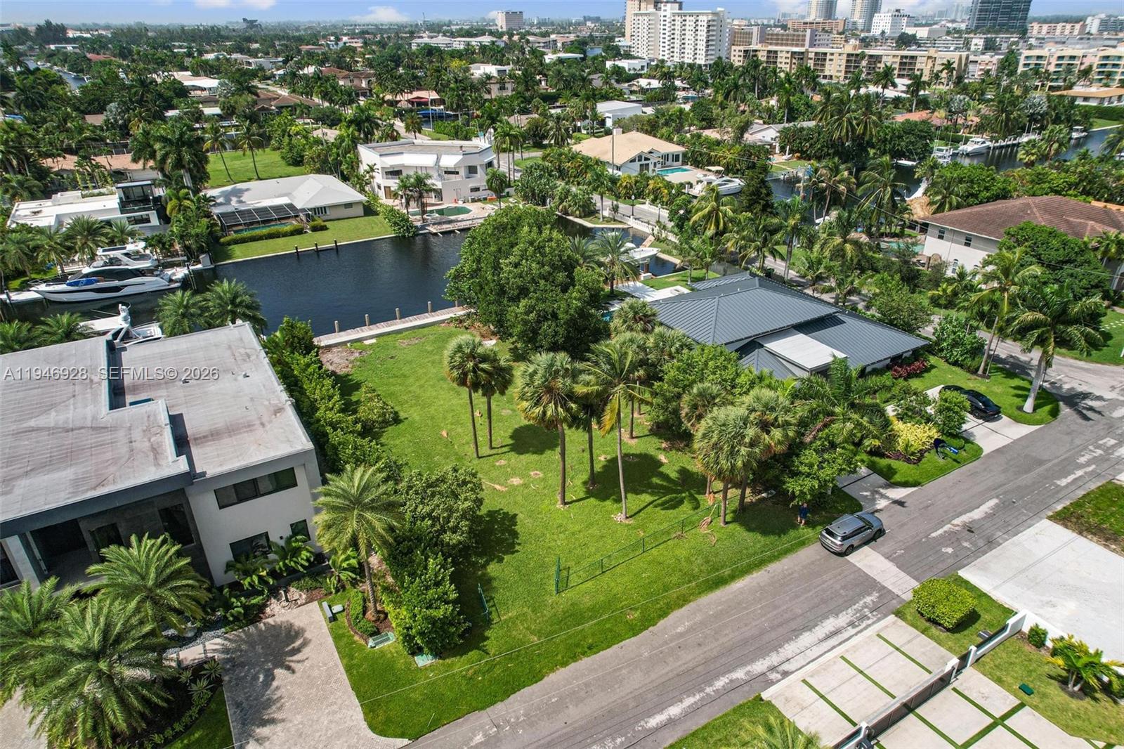 An aerial view shows a residential property with a large lawn, palm trees, and canal — 606 Palm Dr, Hallandale Beach FL 33009, HALLANDALE BEACH, FL