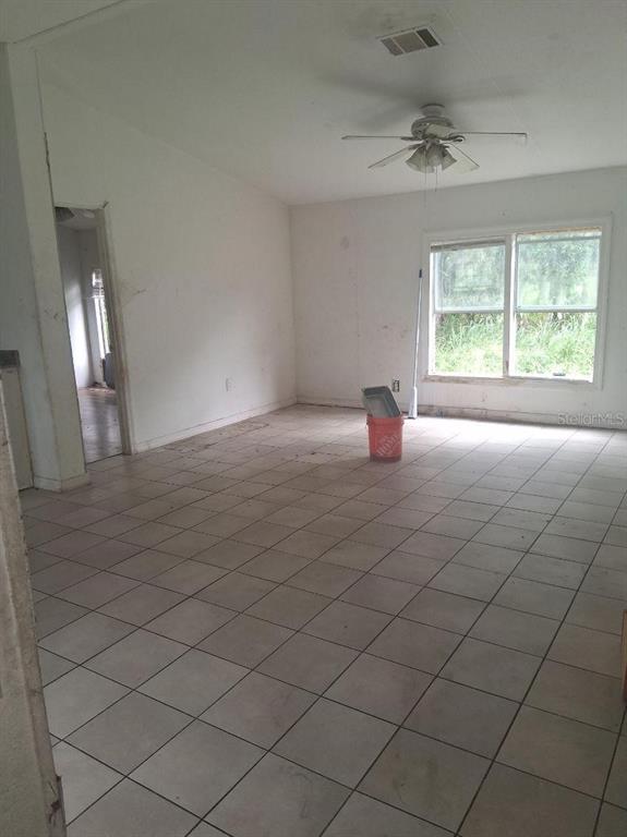 An empty room features white walls, light-colored floor tiles, a ceiling fan, and a window — 3296 LAKE BUFFUM ROAD W, FORT MEADE, FL