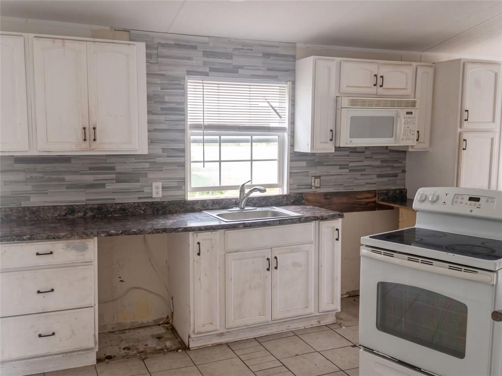 A kitchen features white cabinets, a dark laminate countertop, a window, and a white stove — 3296 LAKE BUFFUM ROAD W, FORT MEADE, FL