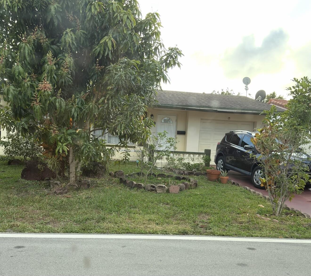 A single-story house with a white door, a garage, and a large tree in front — 4803 Highland Drive, Tamarac FL 33319, TAMARAC, FL