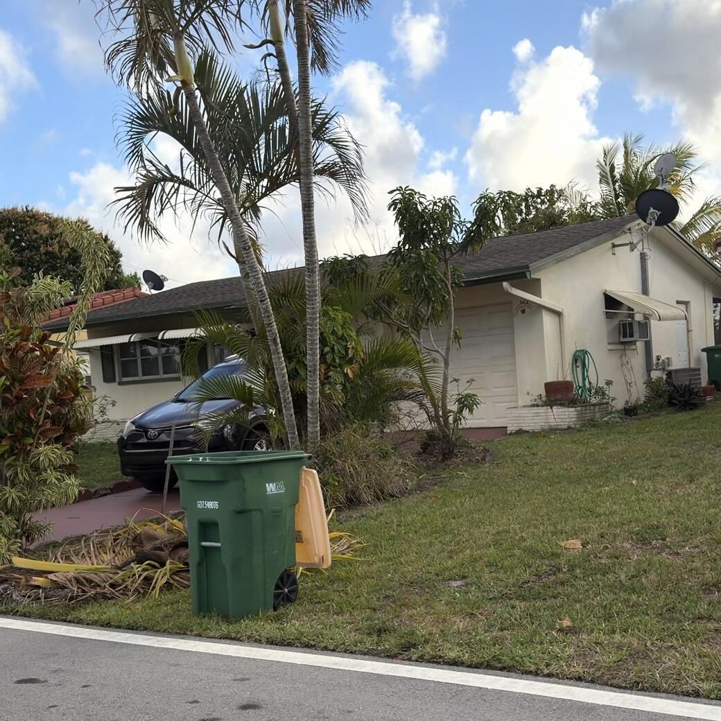 A single-story house with a driveway, a parked car, and a green trash bin outside — 4803 Highland Drive, Tamarac FL 33319, TAMARAC, FL