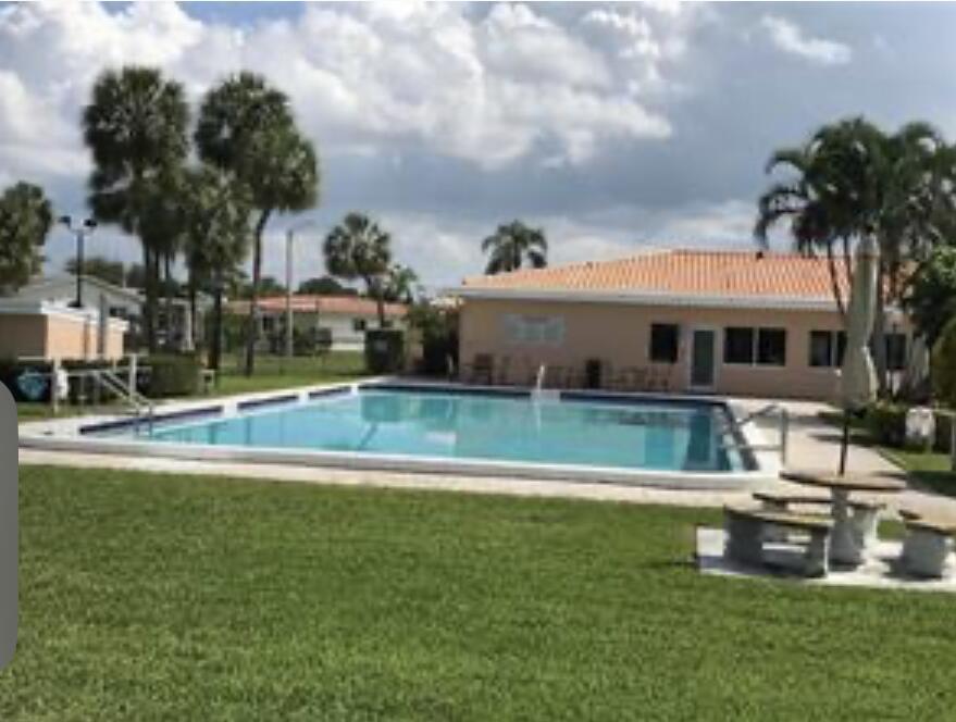 An outdoor swimming pool sits in front of a single-story building with palm trees — 4803 Highland Drive, Tamarac FL 33319, TAMARAC, FL