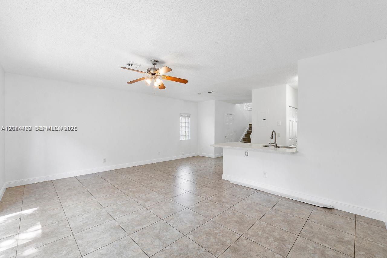 This room features white walls, tile flooring, a ceiling fan, and a kitchen breakfast bar — 16035 Emerald Cove Rd, Weston FL 33331, WESTON, FL