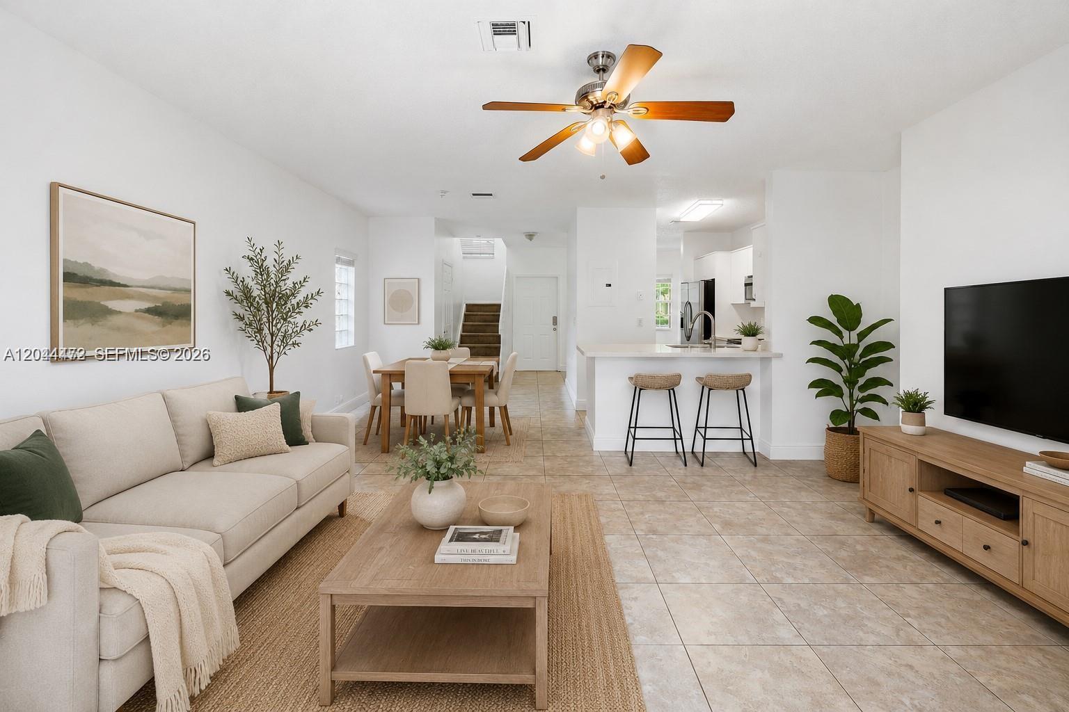 An open-concept living and dining area features light tile flooring, neutral furniture, and a kitchen — 16035 Emerald Cove Rd, Weston FL 33331, WESTON, FL