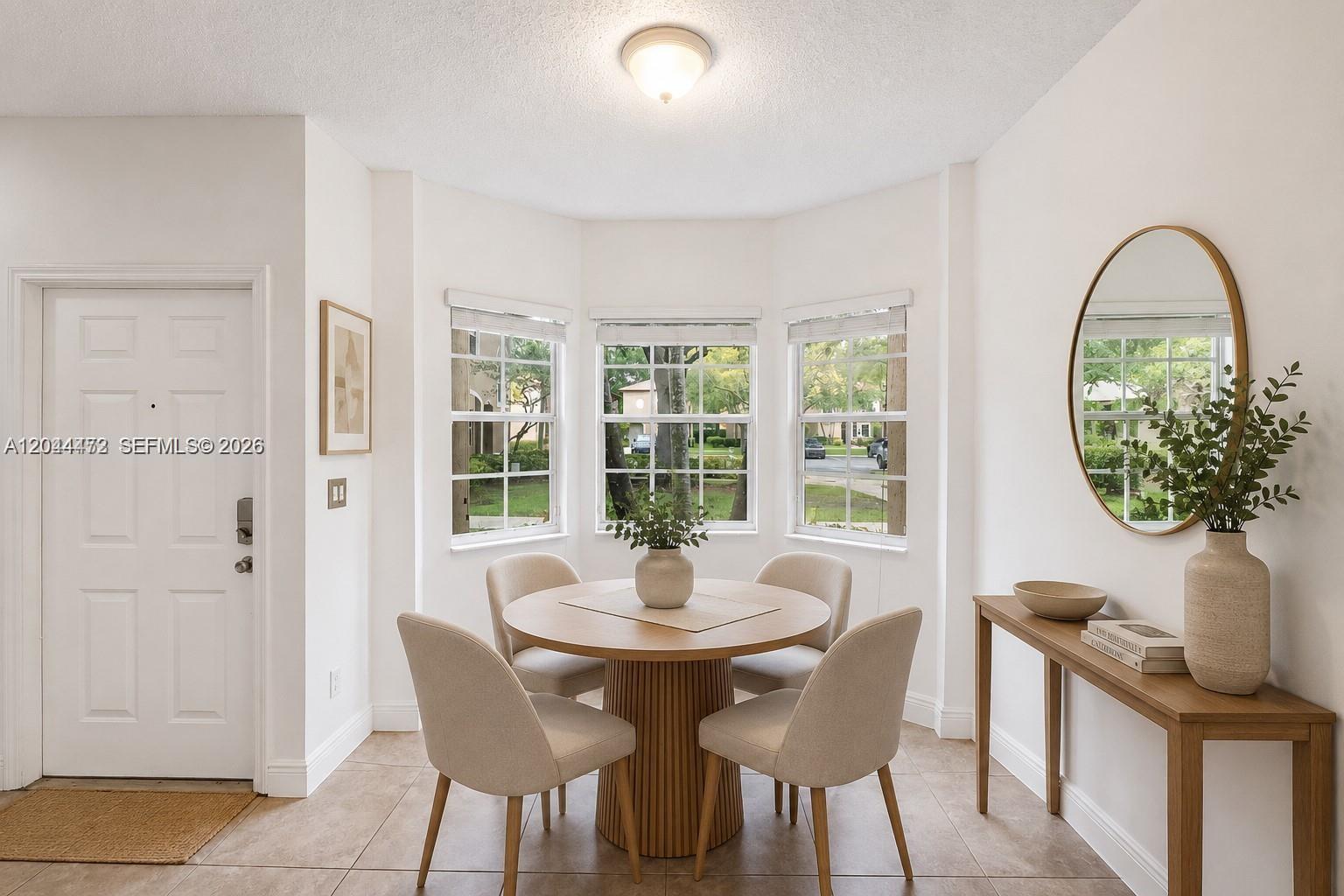 A dining area features a round wooden table, four chairs, and a console table with mirror — 16035 Emerald Cove Rd, Weston FL 33331, WESTON, FL