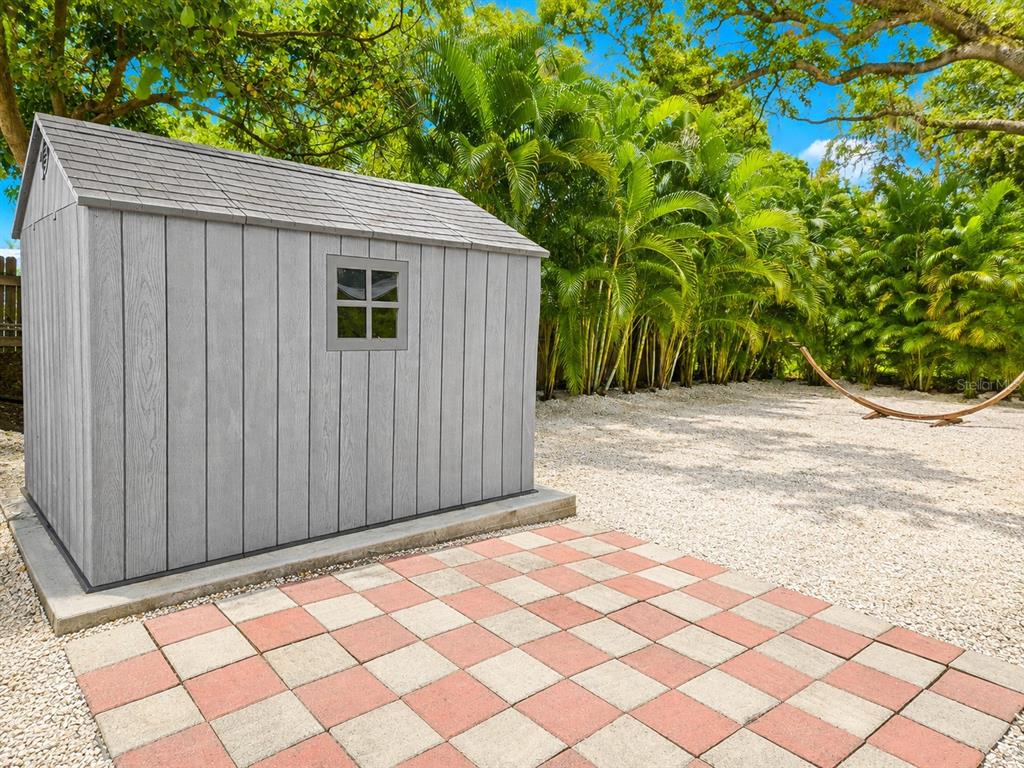 A gray storage shed sits on a concrete pad next to a checkered patio area — 1235 32ND STREET, SARASOTA, FL