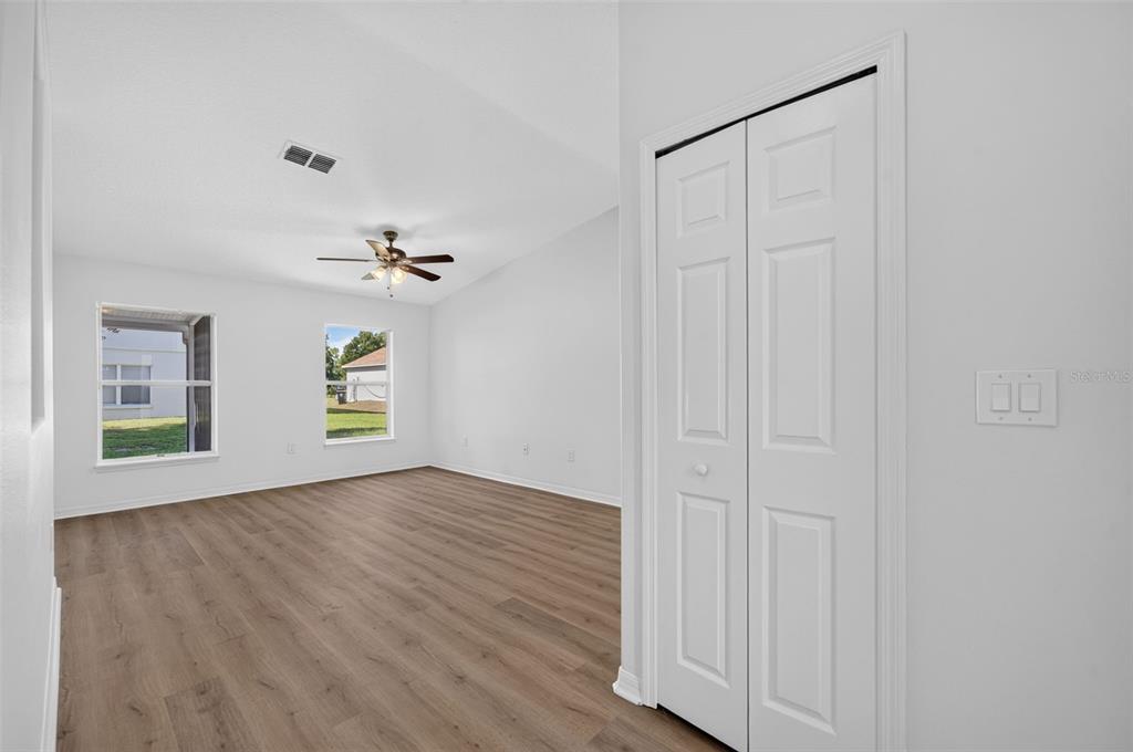An empty room with light wood-look flooring, white walls, a ceiling fan, and a closet — 719 WAXWING COURT, POINCIANA, FL