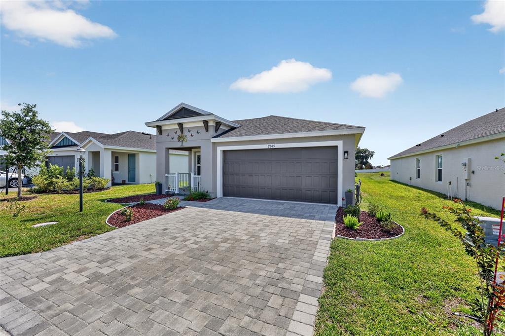 A covered front porch features a paver floor, white railings, and two chairs — 9619 SW 62ND COURT, OCALA, FL