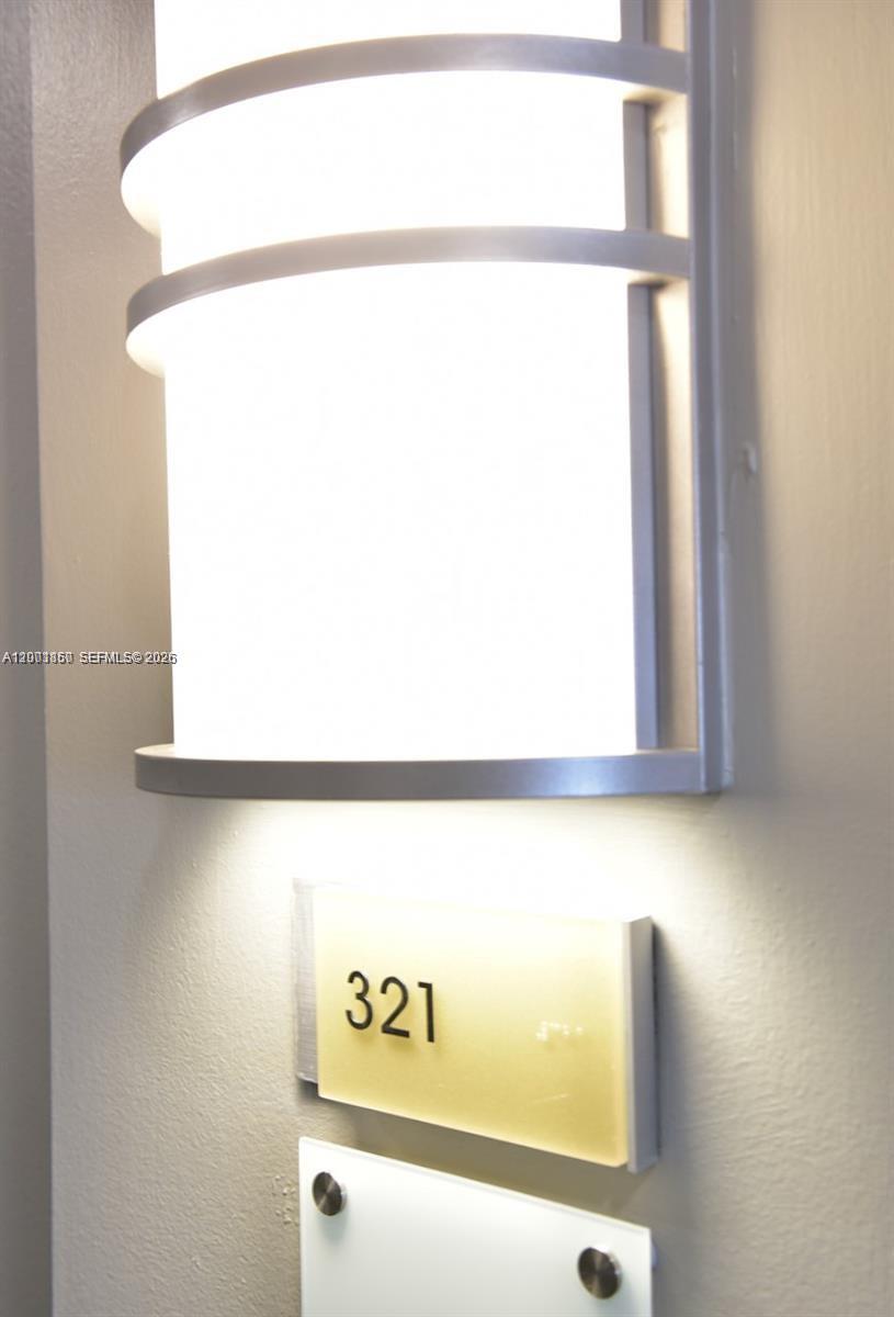 A wall-mounted light fixture illuminates a sign labeled 321 above a blank plaque — 3250 NE 1st Ave # 321, Miami FL 33137, MIAMI, FL