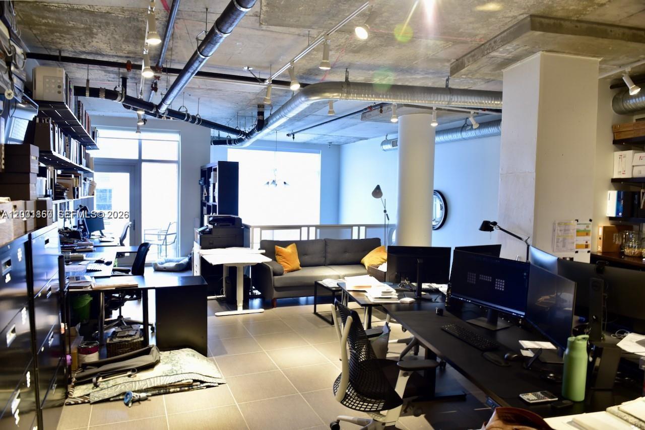 An industrial-style office space features exposed ductwork, concrete ceilings, tile flooring, and multiple workstations — 3250 NE 1st Ave # 321, Miami FL 33137, MIAMI, FL