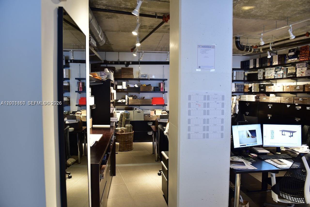 An office space features industrial concrete ceilings, track lighting, and organized shelving units — 3250 NE 1st Ave # 321, Miami FL 33137, MIAMI, FL