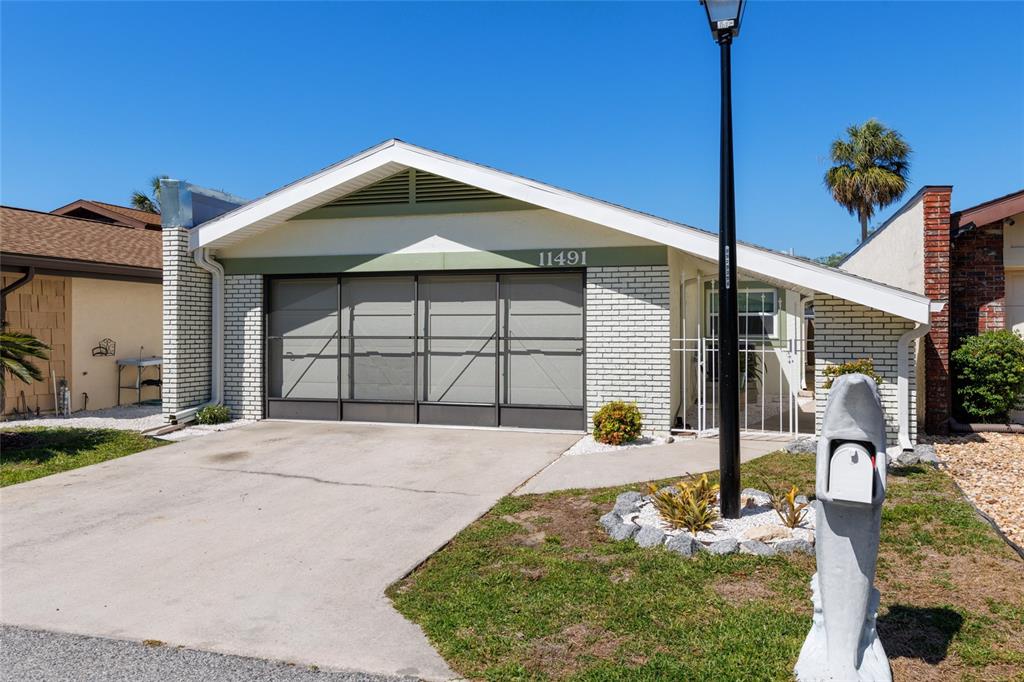 A single-story house with a white brick exterior, a garage screen door, and a dolphin mailbox — 11491 W RIVERHAVEN DRIVE, HOMOSASSA, FL