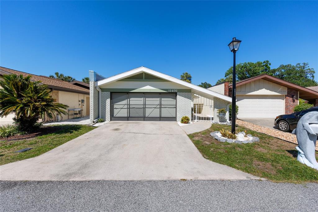 A single-story house with a white brick facade, a garage, and a concrete driveway — 11491 W RIVERHAVEN DRIVE, HOMOSASSA, FL