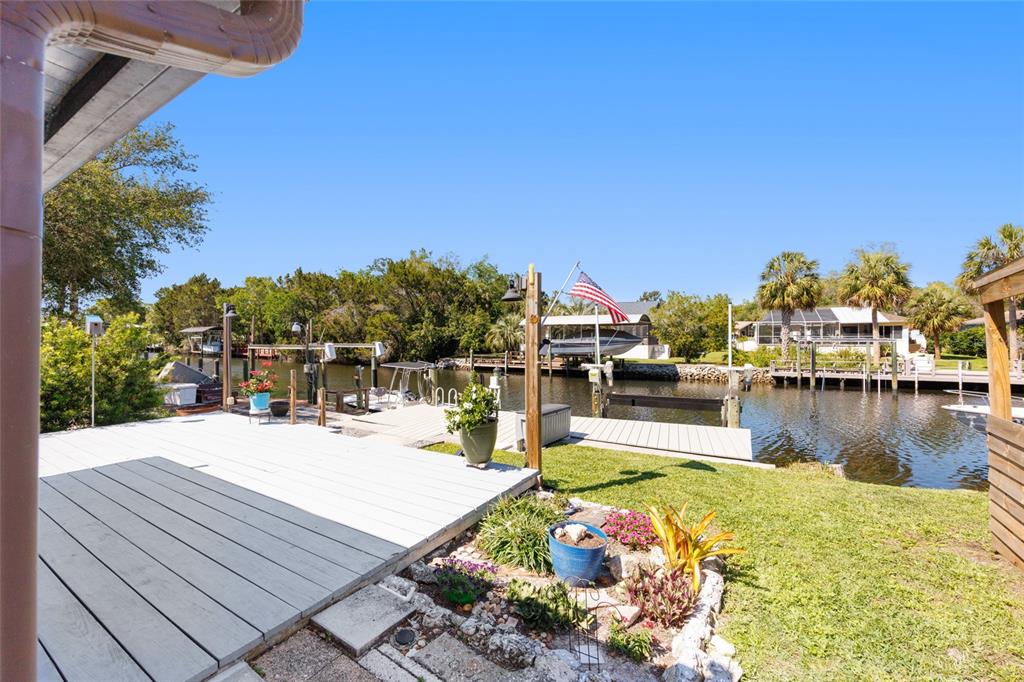 A wooden deck overlooks a canal with boat docks and a small American flag — 11491 W RIVERHAVEN DRIVE, HOMOSASSA, FL