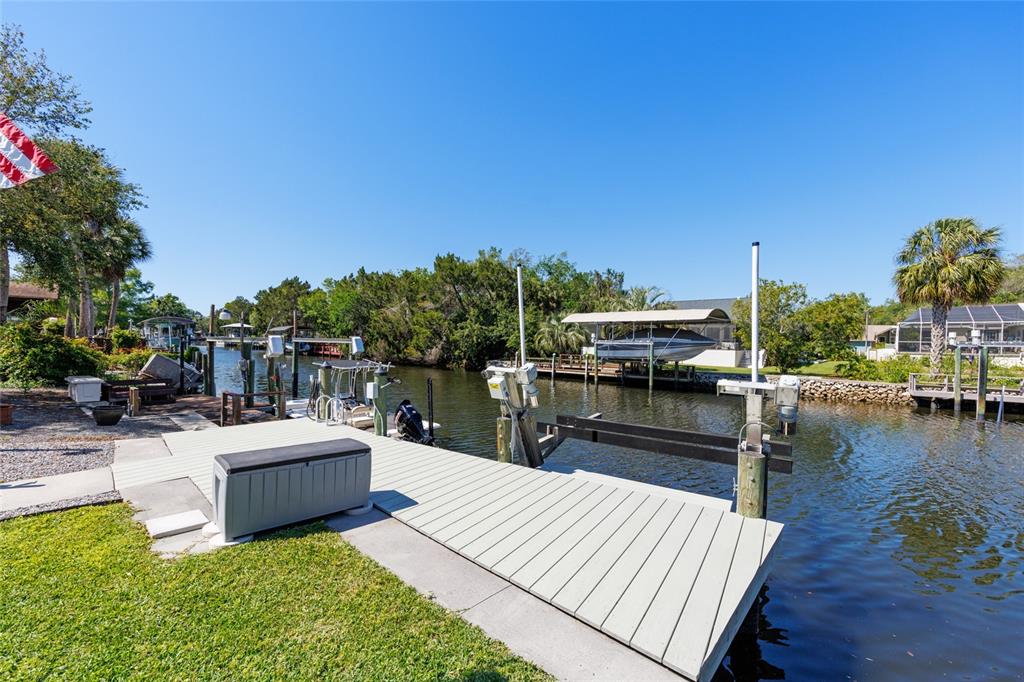 A wooden boat dock with a storage box extends over a canal with boat lifts — 11491 W RIVERHAVEN DRIVE, HOMOSASSA, FL