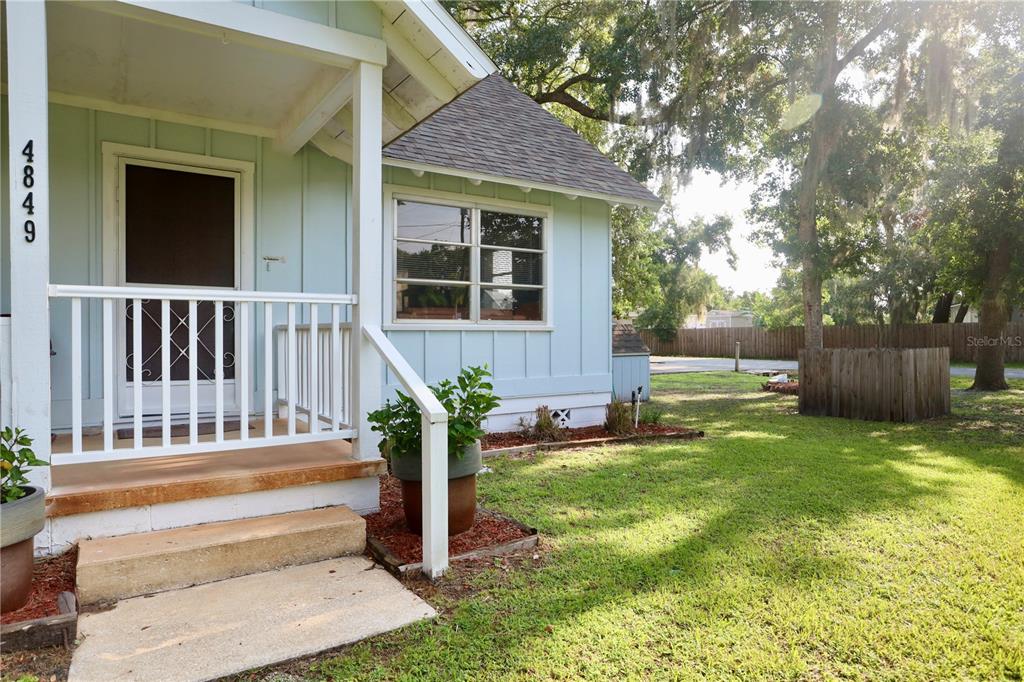 A light blue house exterior features a front porch with white railings and stairs — 4849 MEADOW DRIVE, ST CLOUD, FL