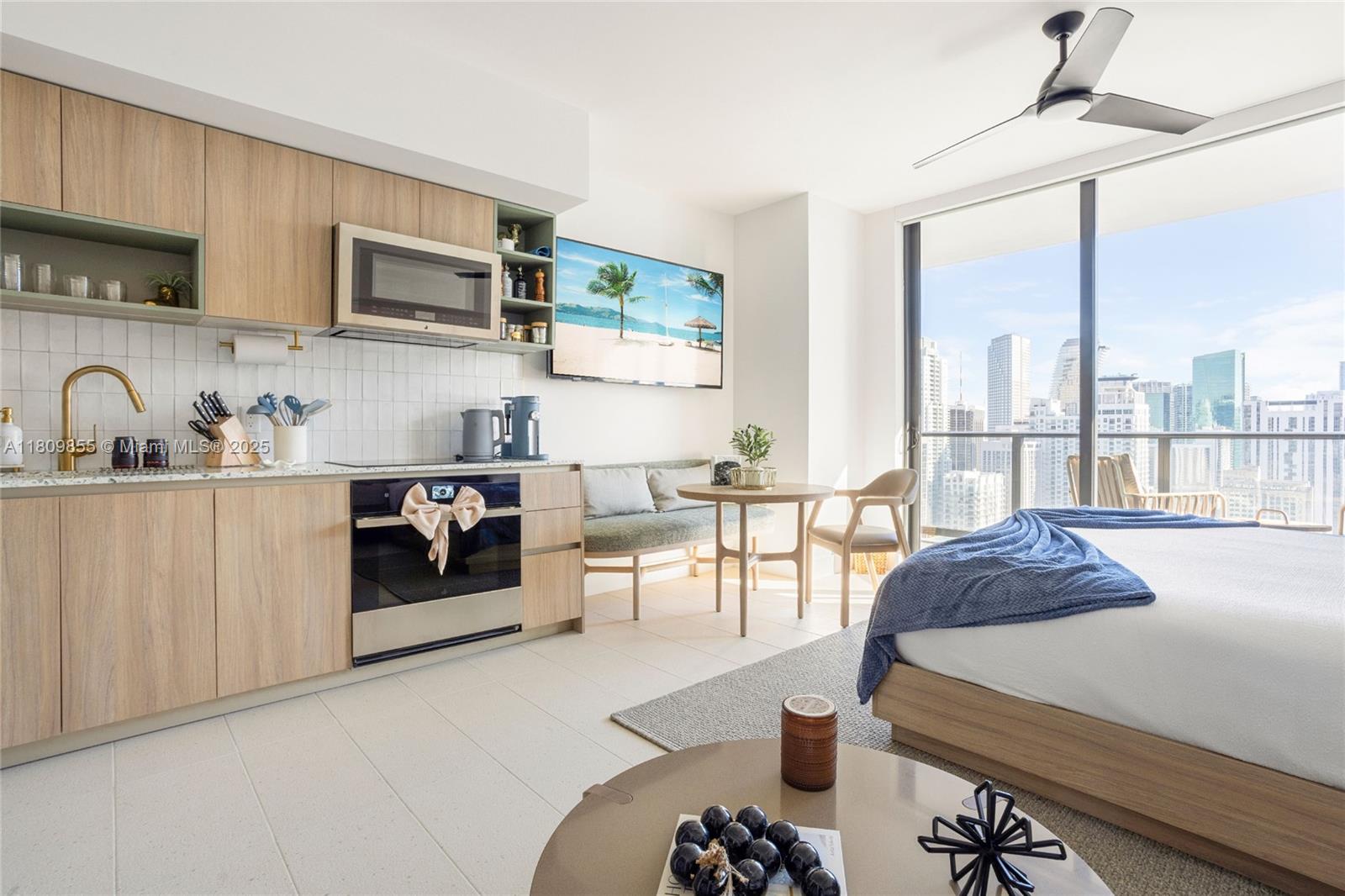 A studio apartment features a kitchenette, dining area, and bed with a city skyline view — 159 NE 6th St # 3012, Miami FL 33132, MIAMI, FL