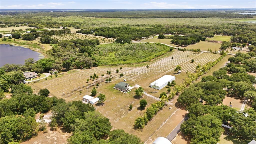An aerial view shows a rural property with a house, outbuildings, and a large pond — 14433 LAKE YALE ROAD, UMATILLA, FL
