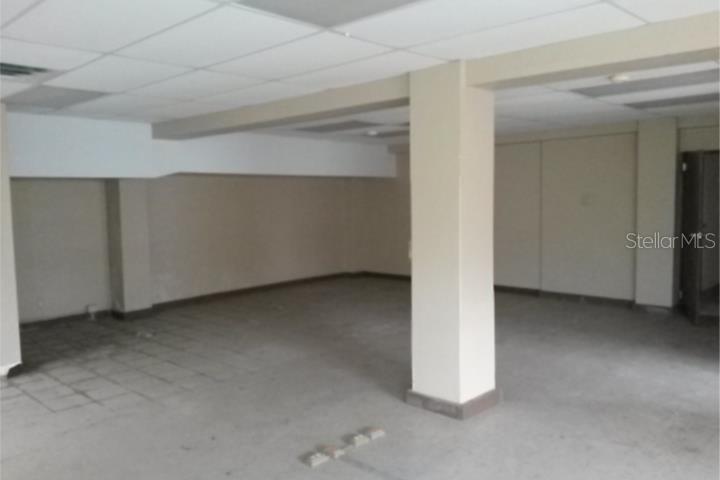 An empty commercial space features a drop ceiling, concrete floors, and a central support column — 11 VELA ST., SAN JUAN, PR