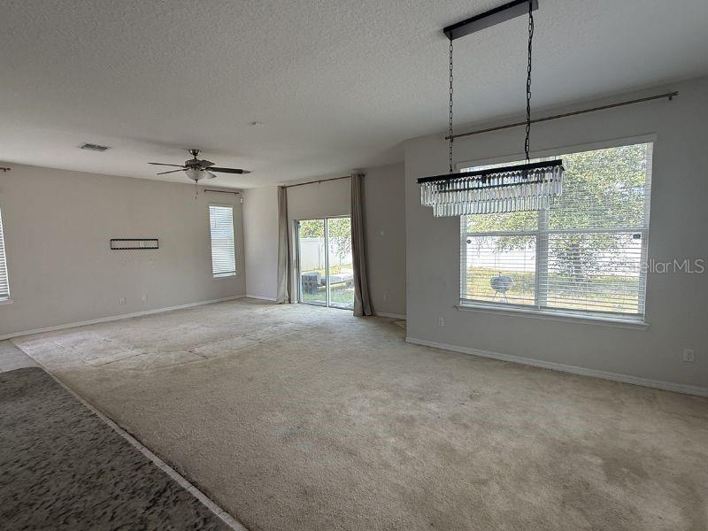 A spacious living area features beige carpeting, a ceiling fan, and a crystal chandelier — 1010 ATLANTIC AVENUE, FRUITLAND PARK, FL