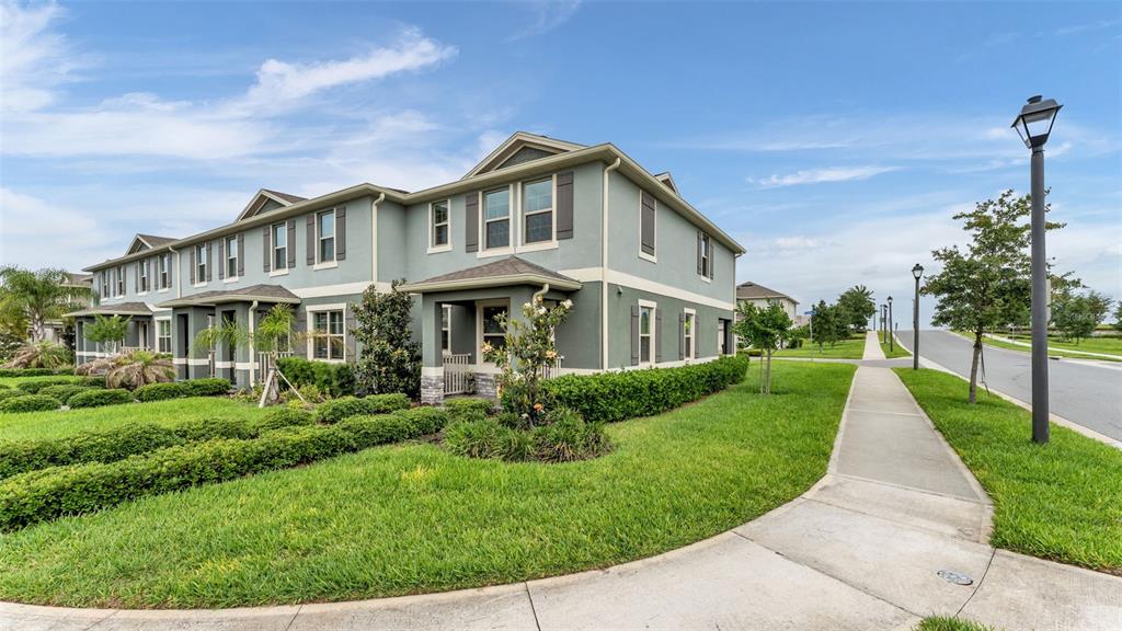 A two-story townhouse with green siding and a front porch sits beside a sidewalk — 12003 HOLYSTONE STREET, WINTER GARDEN, FL