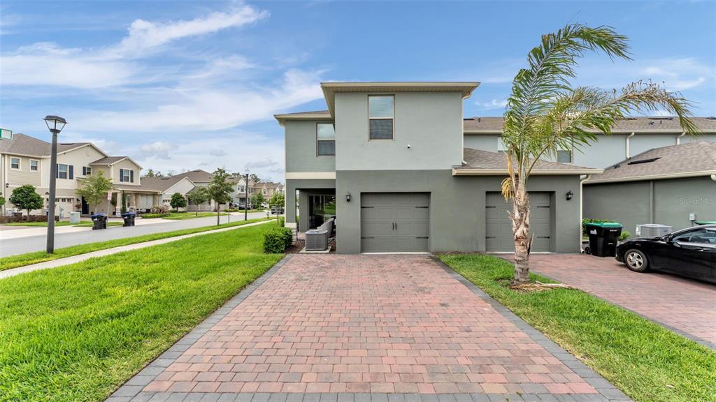 A two-story house with a paved driveway, two garage doors, and a palm tree — 12003 HOLYSTONE STREET, WINTER GARDEN, FL