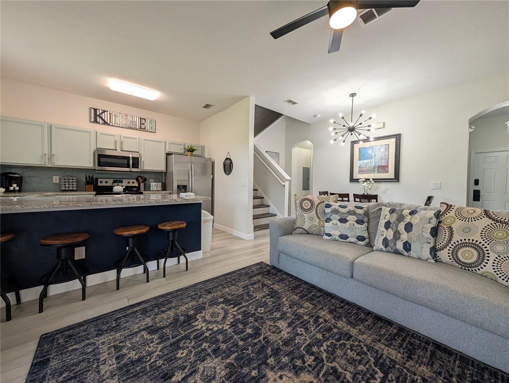 An open-concept kitchen with a breakfast bar overlooks a living area with a gray sofa — 142 CAPRI DRIVE, DAVENPORT, FL
