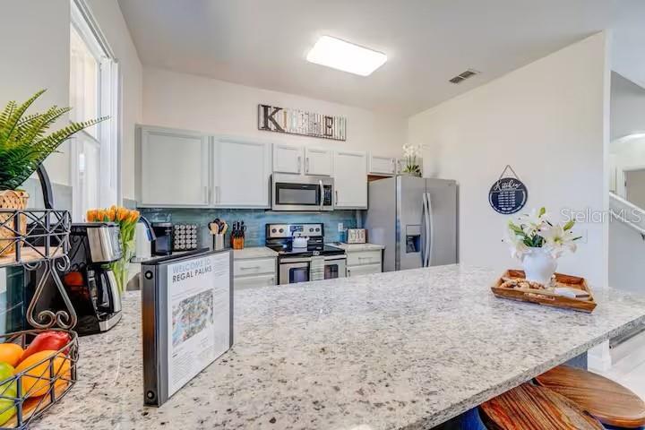 A kitchen features white cabinets, granite countertops, stainless steel appliances, and a central island — 142 CAPRI DRIVE, DAVENPORT, FL