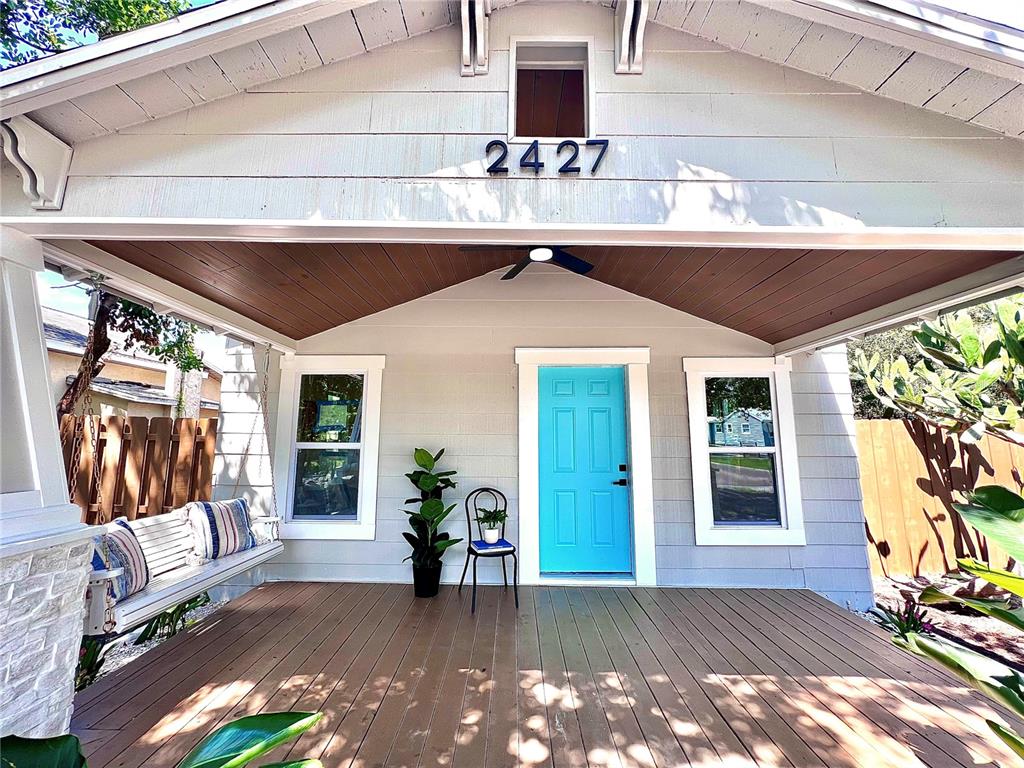 A front porch features a wooden deck, a hanging swing, and a bright blue front door — 2427 32ND AVENUE N, ST PETERSBURG, FL